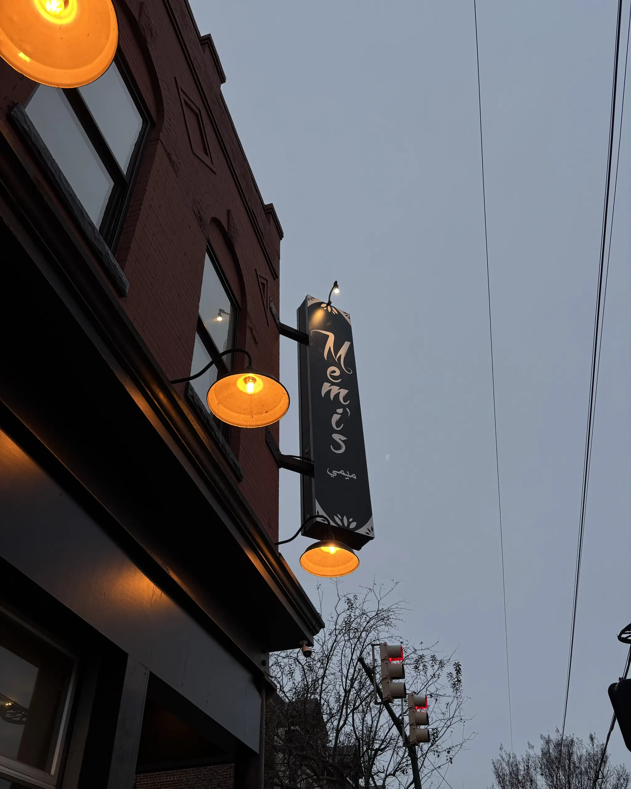 Memi’s — blade sign with the finished logo mounted outside the restaurant at dusk